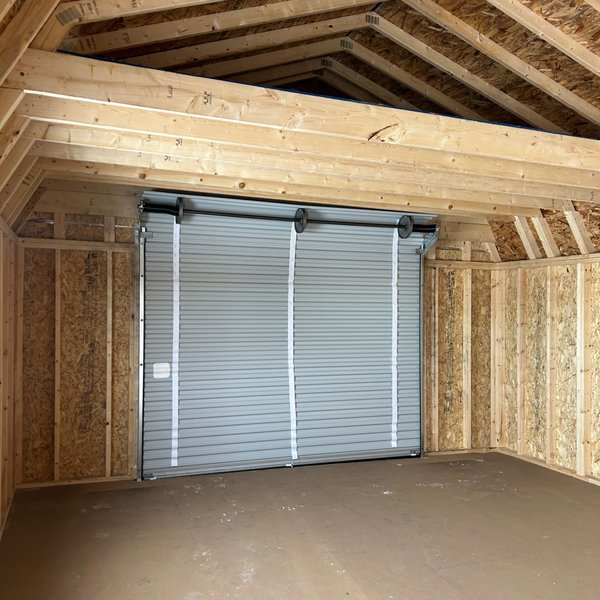 Interior of a Premier portable garage showing the roll-up door and roof trusses